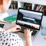uma mulher sentada fazendo marcacoes online pelo computador do ebooking e airbnb